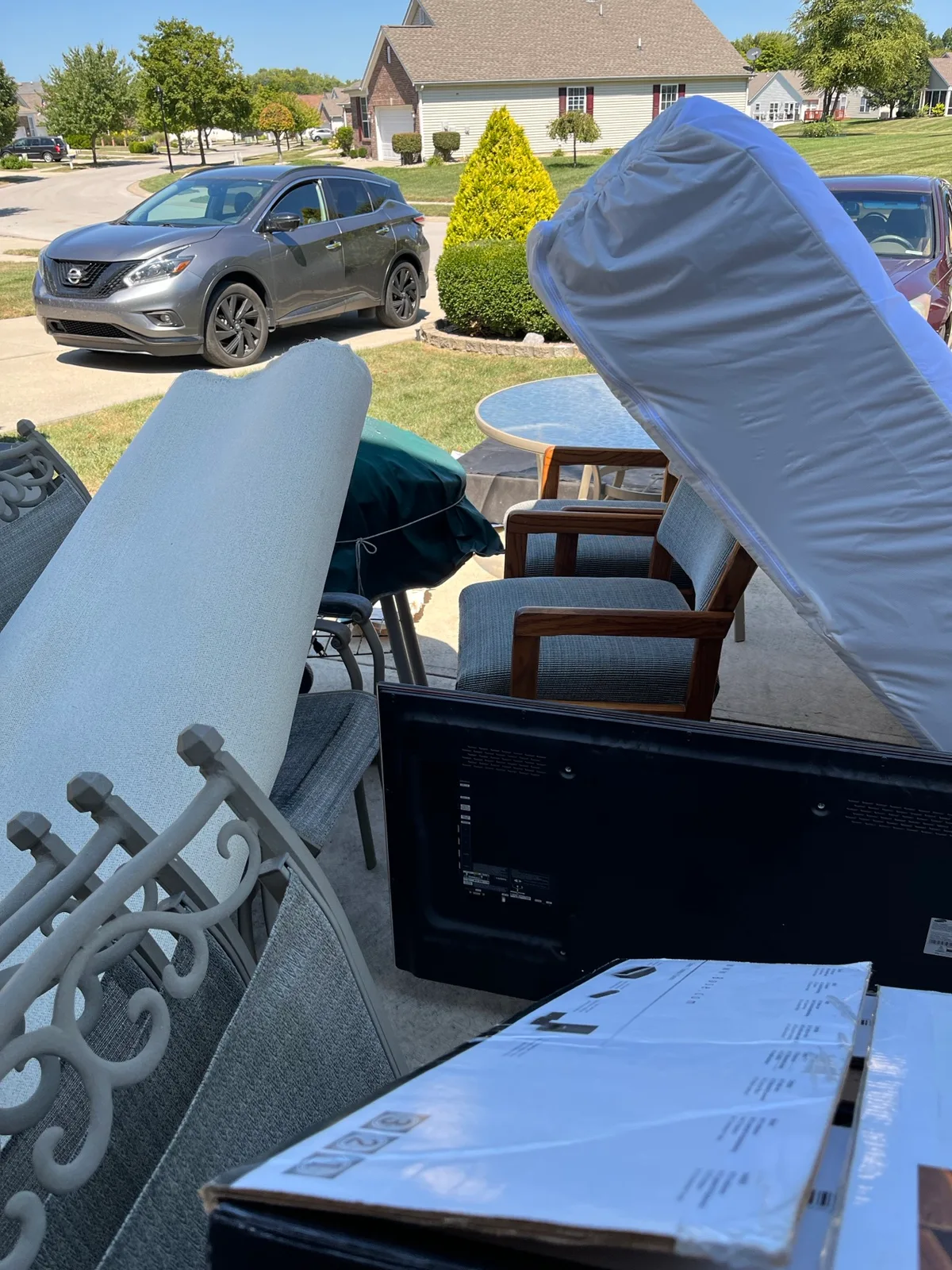 A spring cleaning staging pile done right: patio table, chairs, and a TV set outside and ready for pickup in Indianapolis
